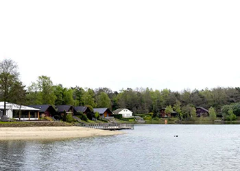 Vakantiepark aan het meer met strand en huisjes. Bosrijke omgeving, rustige sfeer.